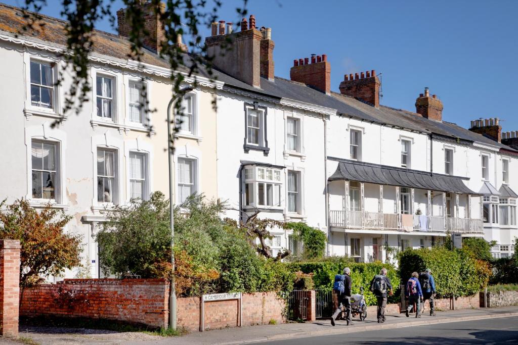Un grupo de personas en bicicleta frente a casas blancas. en Cambridge House, en Sidmouth