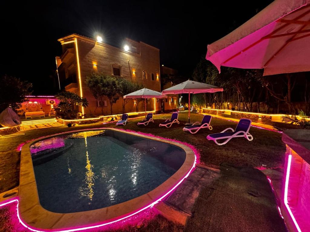 a swimming pool with chairs and umbrellas at night at فيلا إيجار في التجمع الخامس Vip Luxury home in Cairo