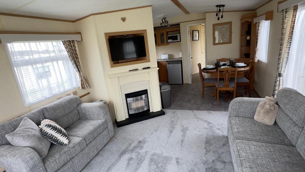 a living room with two couches and a fireplace and a table at Coastal Caravan in Solva in Haverfordwest