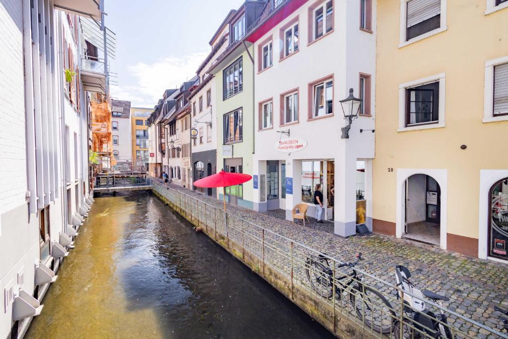 a canal in a city with buildings and a red umbrella at Altstadtsuite City Center in Freiburg im Breisgau