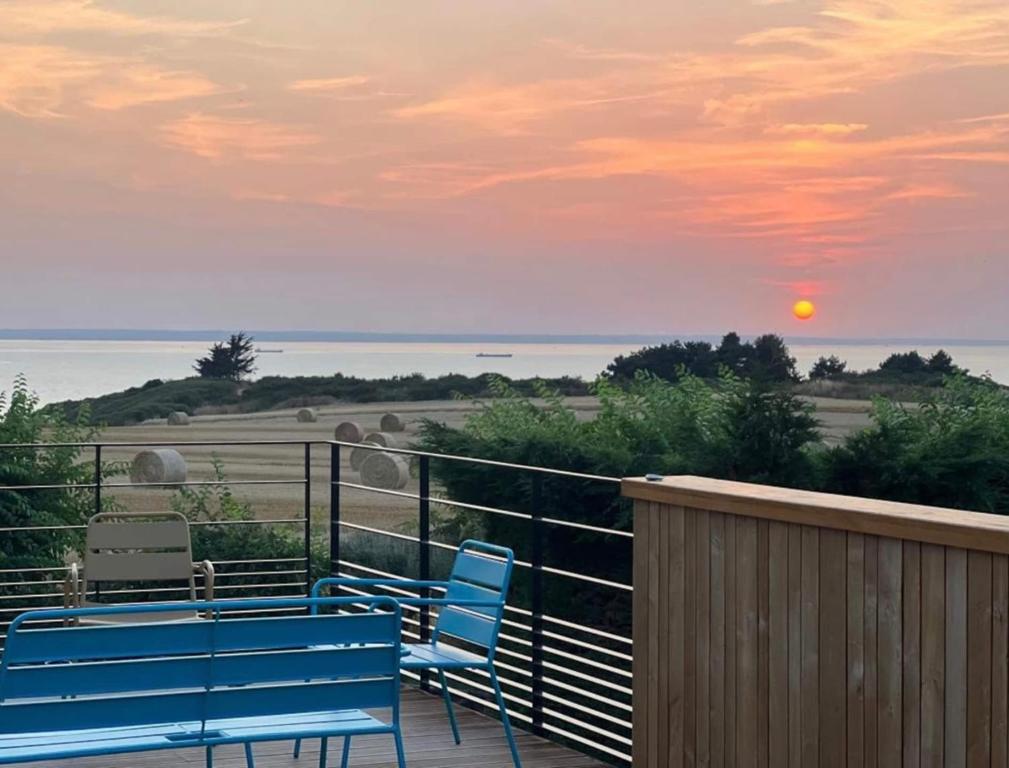 - deux chaises bleues et une table sur un balcon avec vue sur le coucher du soleil dans l'établissement Le Refuge Marin, à Dahouet