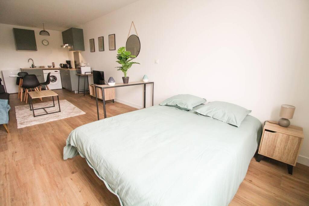 Cet appartement comprend une chambre avec un lit blanc et une cuisine. dans l'établissement NEW La Casa 1 grand studio rénové, Wifi, à Angoulême