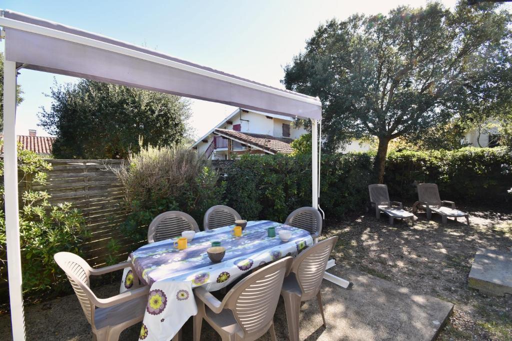 - une table avec des chaises et un auvent blanc dans la cour dans l'établissement Aire Ona 2 - Hossegor appartement situé à proximité de la plage de la gravière, à Soorts-Hossegor