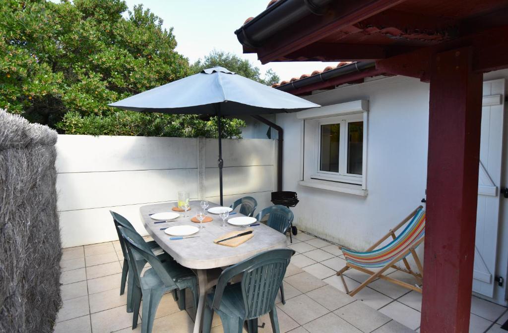 une table et des chaises avec un parasol sur une terrasse dans l'établissement Aire Ona 1 - Hossegor appartement situé à deux pas de la plage de la gravière, à Soorts-Hossegor