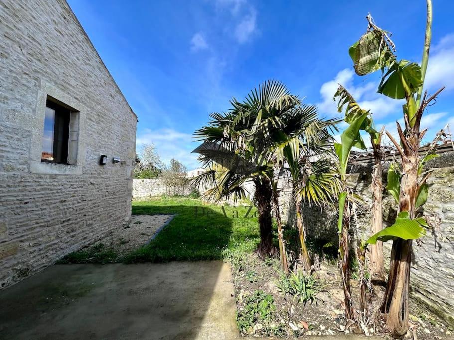 a group of trees next to a brick building at Le Nid Marin - Spacieuse maison avec jardin in Moëze