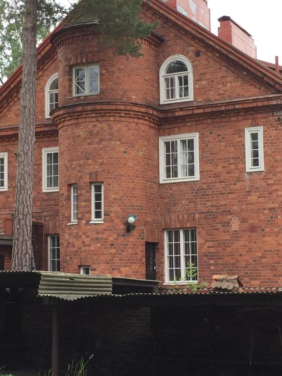 a red brick building with white windows and a tree at Famous Villa Bertel Jung in Helsinki