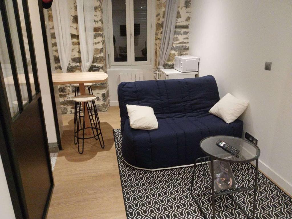 - un salon avec un canapé bleu et un tabouret dans l'établissement Petit studio, à Millau