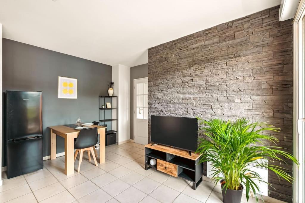 un salon avec une télévision et un mur en briques dans l'établissement T2 paisible Vaise, avec parking métro direct Bellecour, à Lyon