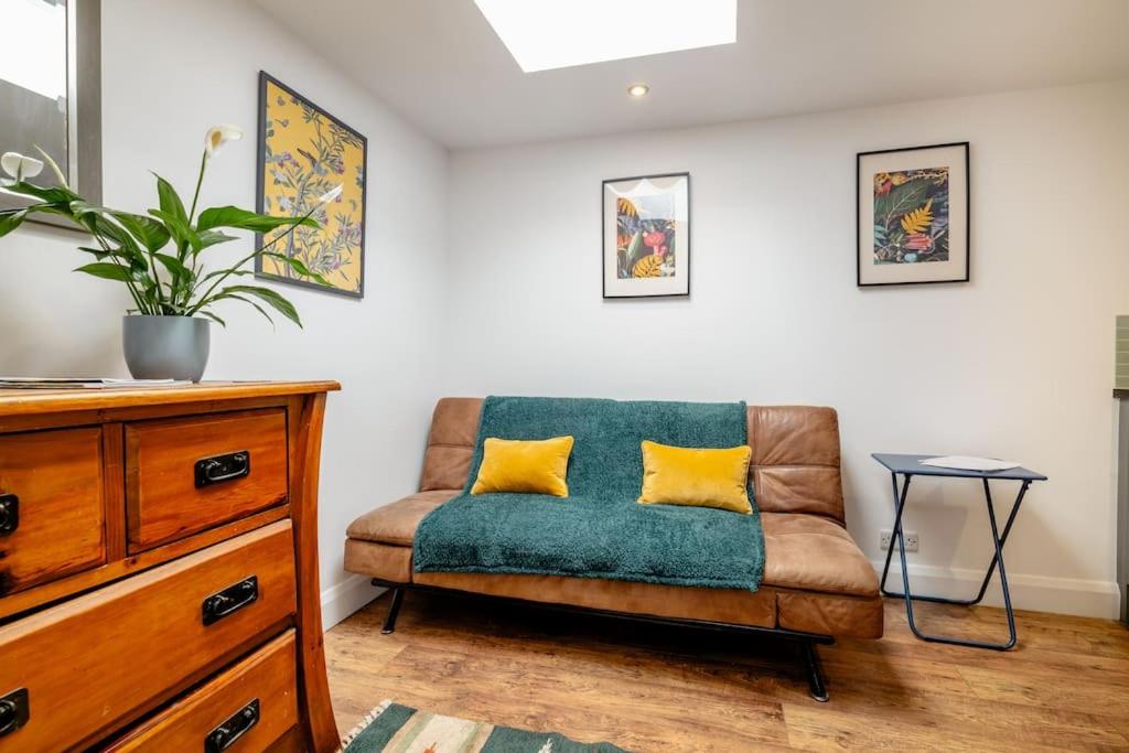 a living room with a couch with two yellow pillows at Self contained two room studio apartment, own entrance, private parking in Brighton & Hove