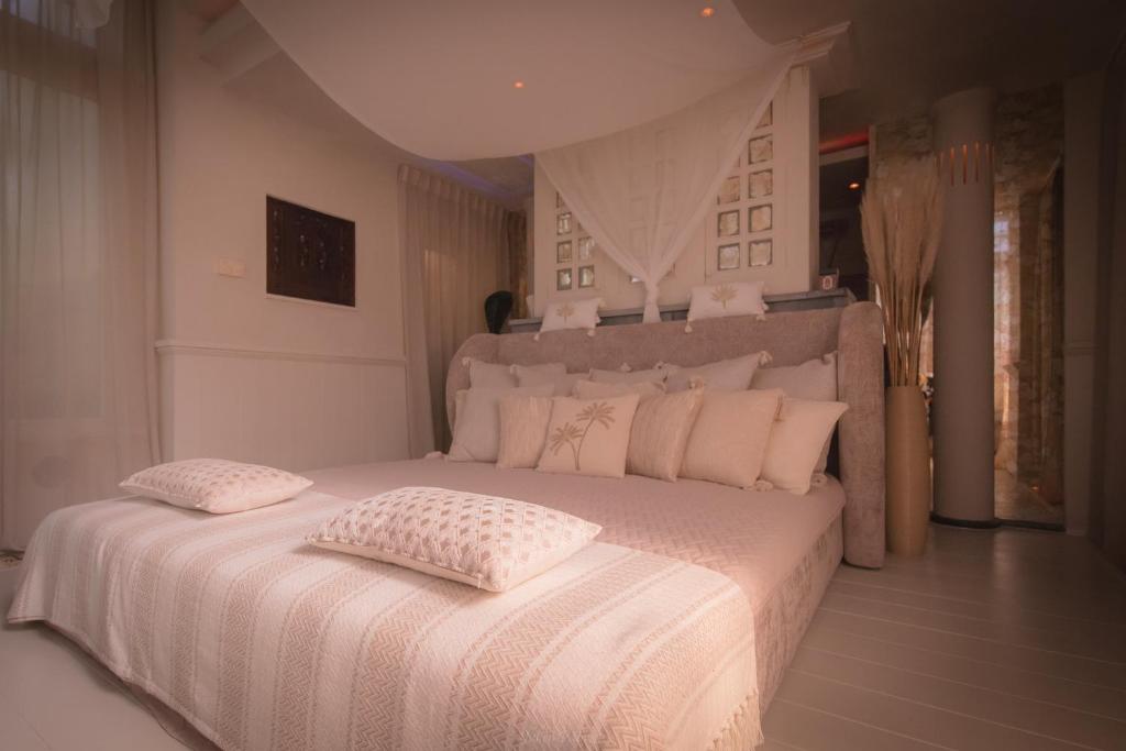 una camera bianca con un grande letto con lenzuola e cuscini bianchi di Evāra a Herk-de-Stad