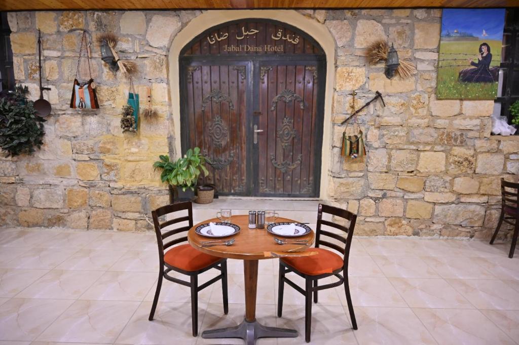 ein Holztisch und Stühle vor einer Tür in der Unterkunft Jabal Dana Hotel - the highest hotel in Jordan in Dana
