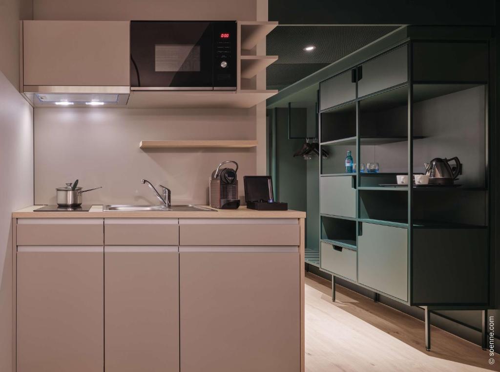 a kitchen with white and green cabinets and a sink at Dorint Hotel Bonn in Bonn