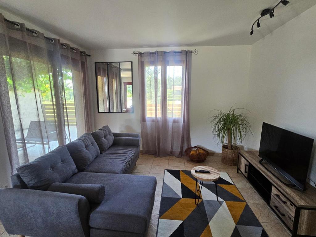 un salon avec un canapé bleu et une télévision dans l'établissement Gite du Chêne Pardaillan, à Pardaillan