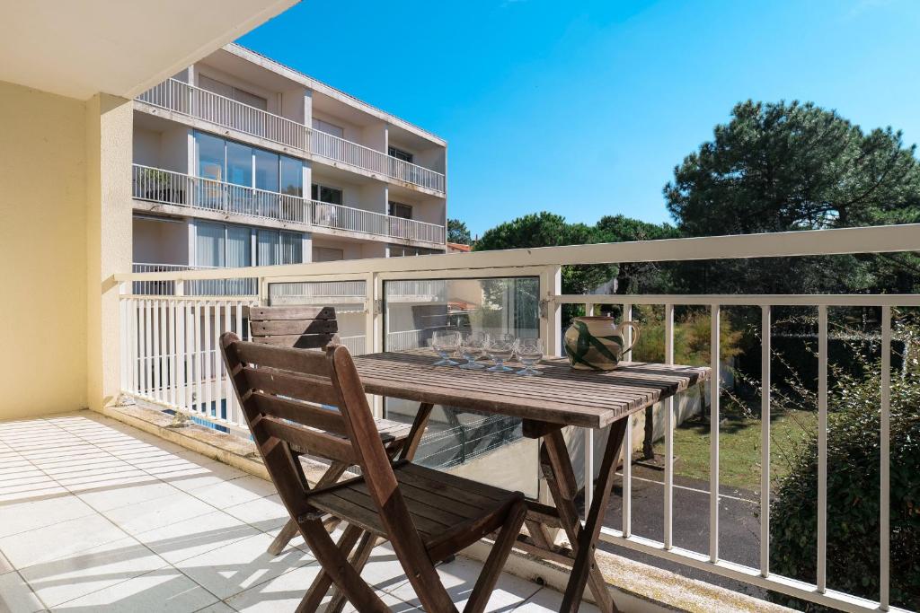 a deck with a wooden table and chairs on a balcony at Appartement proche plage, quartier des Présidents, Les Sables - 4 personnes in Les Sables-dʼOlonne