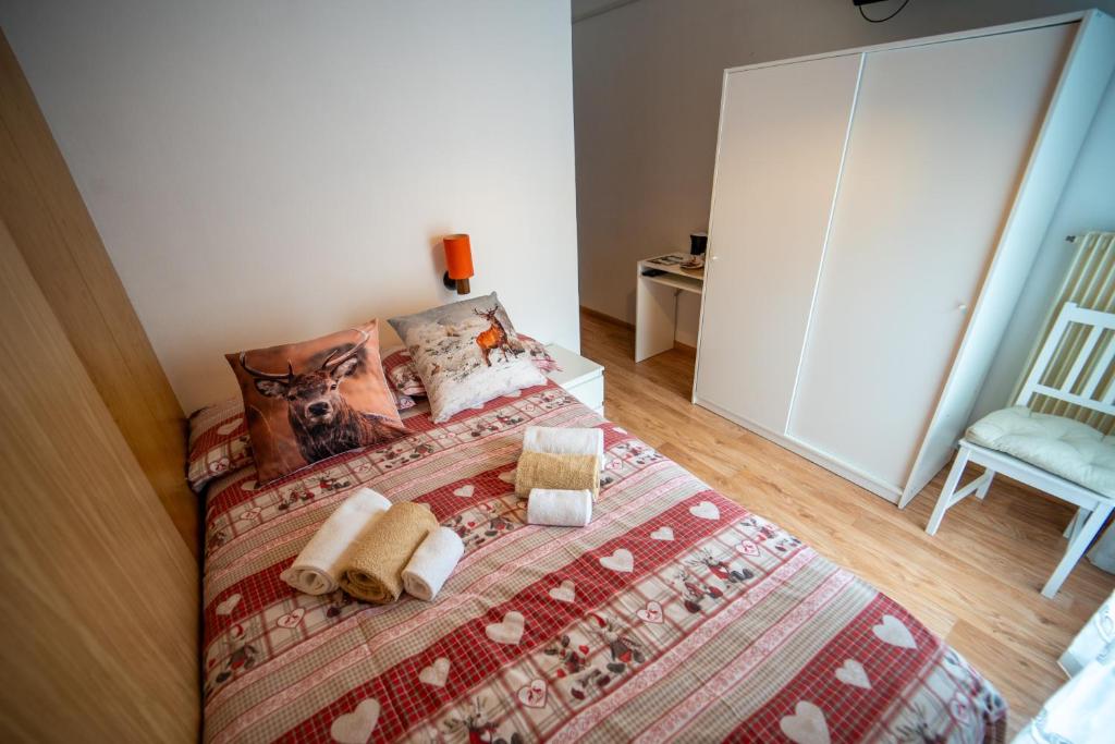 a bedroom with a bed with a blanket and a chair at Cèsa Cherpei - Dog Friendly in Campitello di Fassa