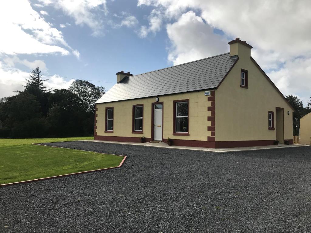 3 bedroom cottage near Kilrush & Doonbeg في غابات كيلرَش: منزل صغير أمامه ممر حصى