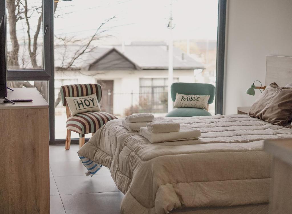 1 Schlafzimmer mit einem Bett mit 2 Stühlen und einem Fenster in der Unterkunft Gente del Sur - Buena Vista in Ushuaia