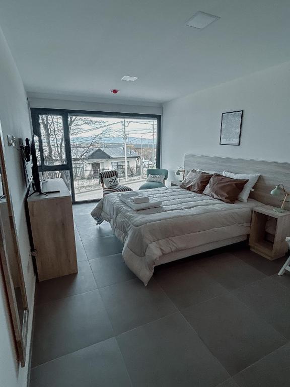 a bedroom with a large bed and a large window at Gente del Sur - Buena Vista in Ushuaia