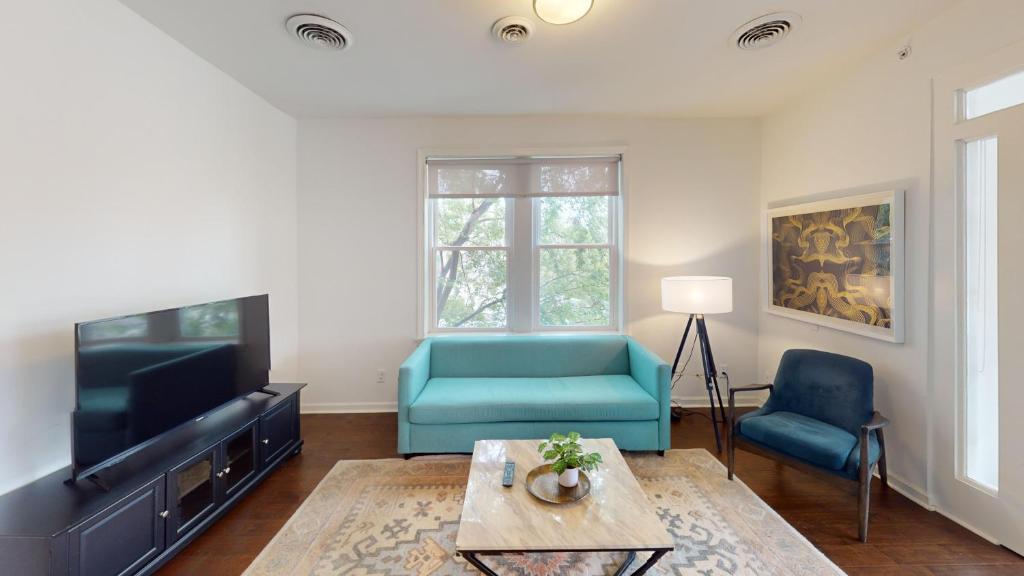 a living room with a tv and two blue chairs at Nashville West End Getaway in Nashville