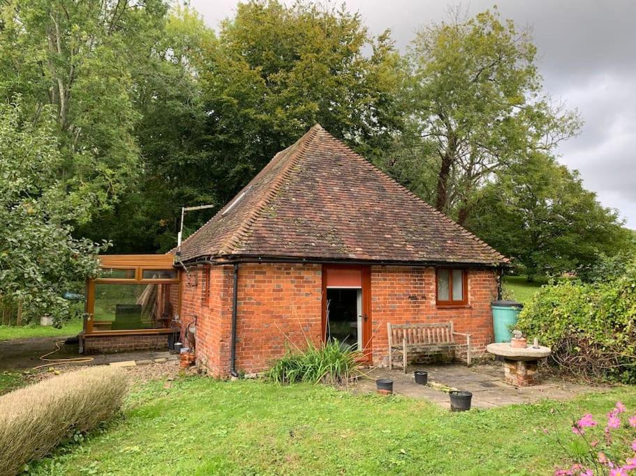 a small brick house with a bench in a yard at The Tanyard in West Malling