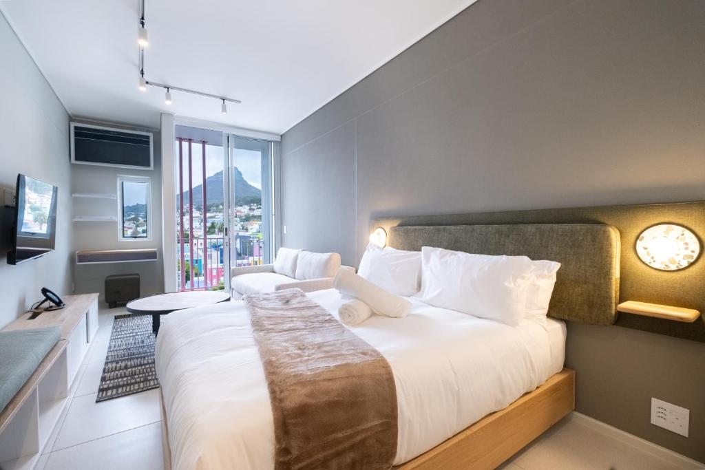 una camera da letto con un grande letto con un orologio sul muro di The Rose 704: Top Floor Modern Studio Apartment a Città del Capo