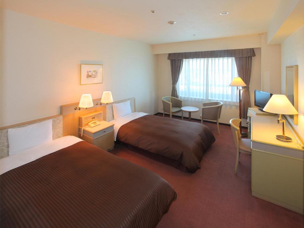 a hotel room with two beds and a desk at Hotel Green Tower Makuhari in Chiba