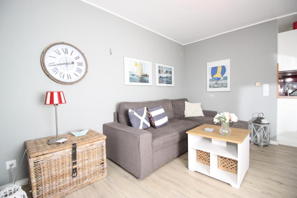 a living room with a couch and a clock on the wall at Ort Lemkenhafen Ostseeperle in Fehmarn