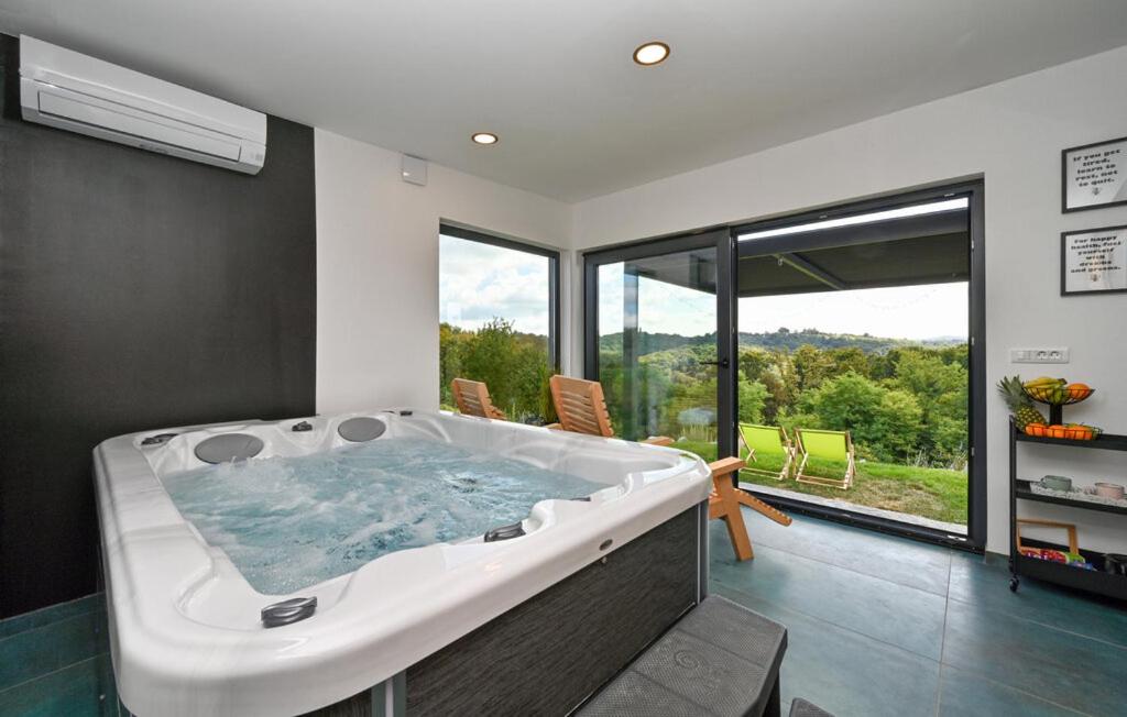 a large bath tub in a room with a large window at Wellness Villa Silente with spa area in Jalšovec
