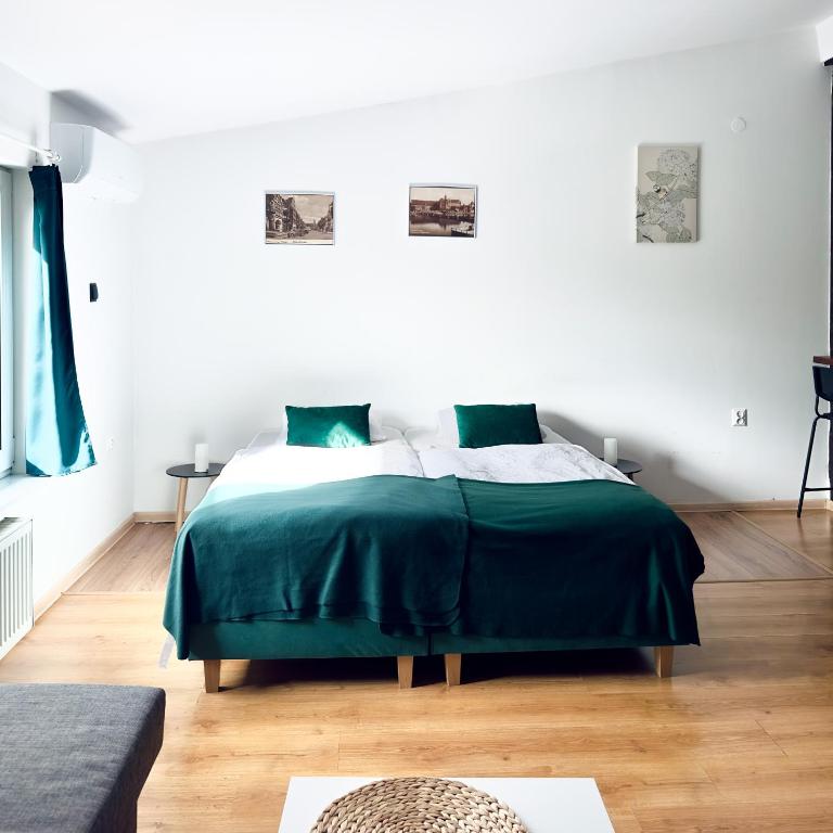 a bedroom with a bed with a green blanket at Główna Apartamenty Nad Nogatem in Malbork