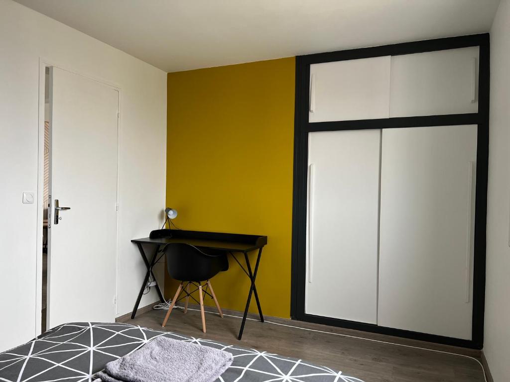 a bedroom with a sliding door and a desk at chambre privée jaune dans appartement partagé in Orléans