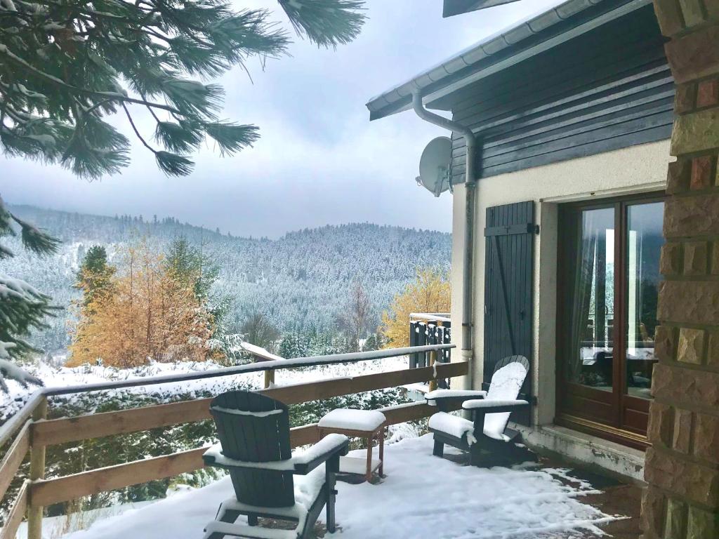 2 Stühle und ein Tisch auf einer Veranda im Schnee in der Unterkunft Grand chalet de charme cosy, sauna & vue de rêve in Ban-sur-Meurthe-Clefcy