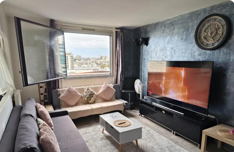 un salon avec un canapé et une télévision à écran plat dans l'établissement Grand appartement proche métro quartier la defense, à Courbevoie