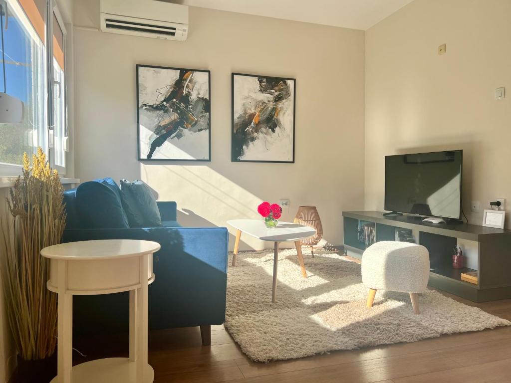 a living room with a blue couch and a tv at Venus Apartment in Kŭrdzhali