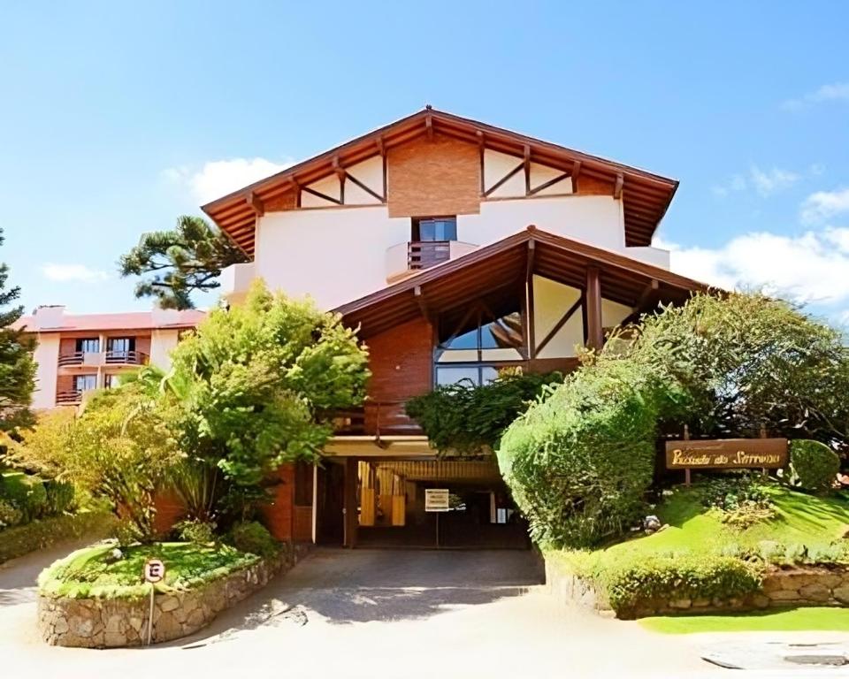 un grande edificio con alberi di fronte di Apartamento Pousada do Serrano a Gramado