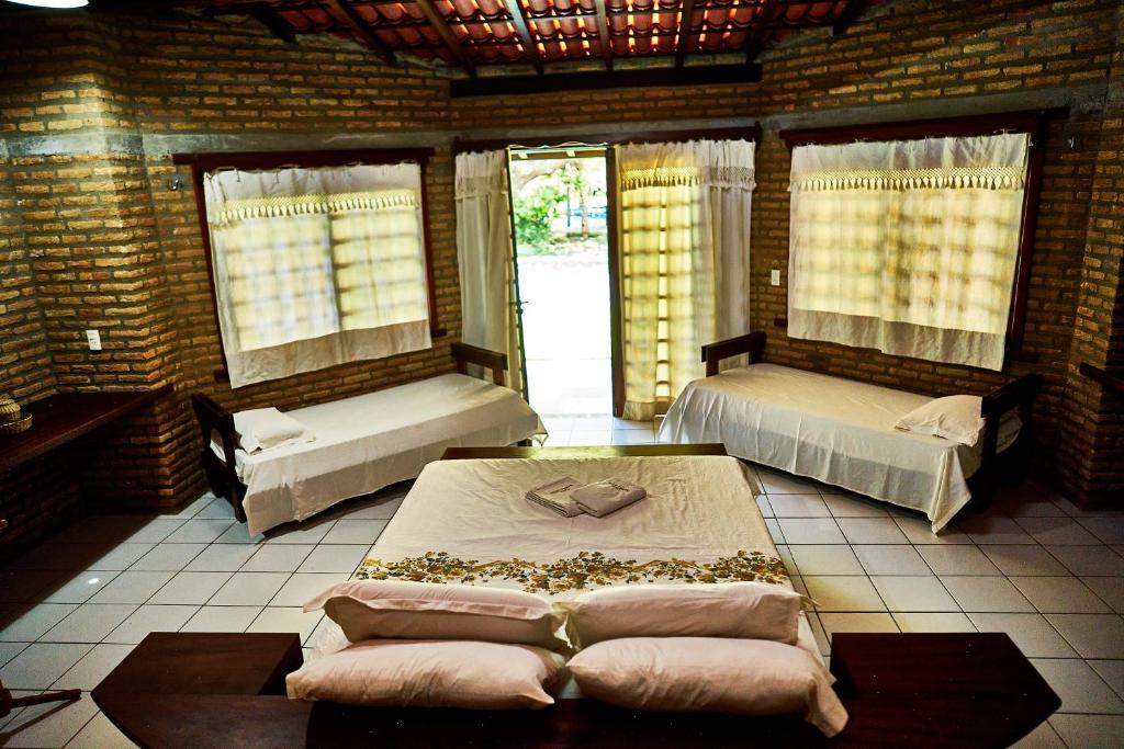 een kamer met 2 bedden, een tafel en ramen bij Casa Barra Nova in Cascavel