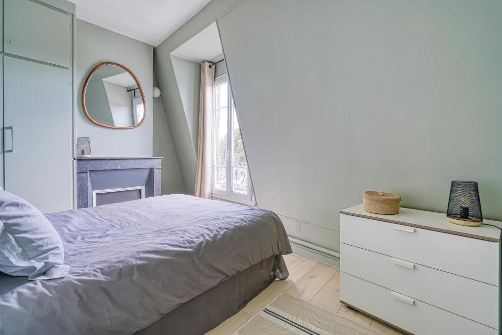 une chambre avec un lit et un miroir dans l'établissement F2 Parisien - Père Lachaise, à Paris