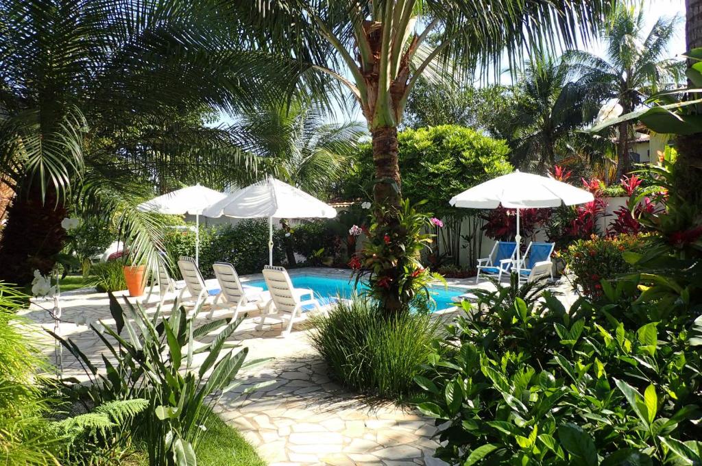 a swimming pool with chairs and umbrellas and a pool at Maris Paraty in Paraty