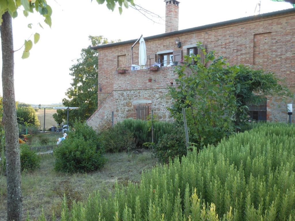une ancienne maison en briques avec un jardin en face de celle-ci dans l'établissement Agriturismo Santa Maria, à Torrita di Siena