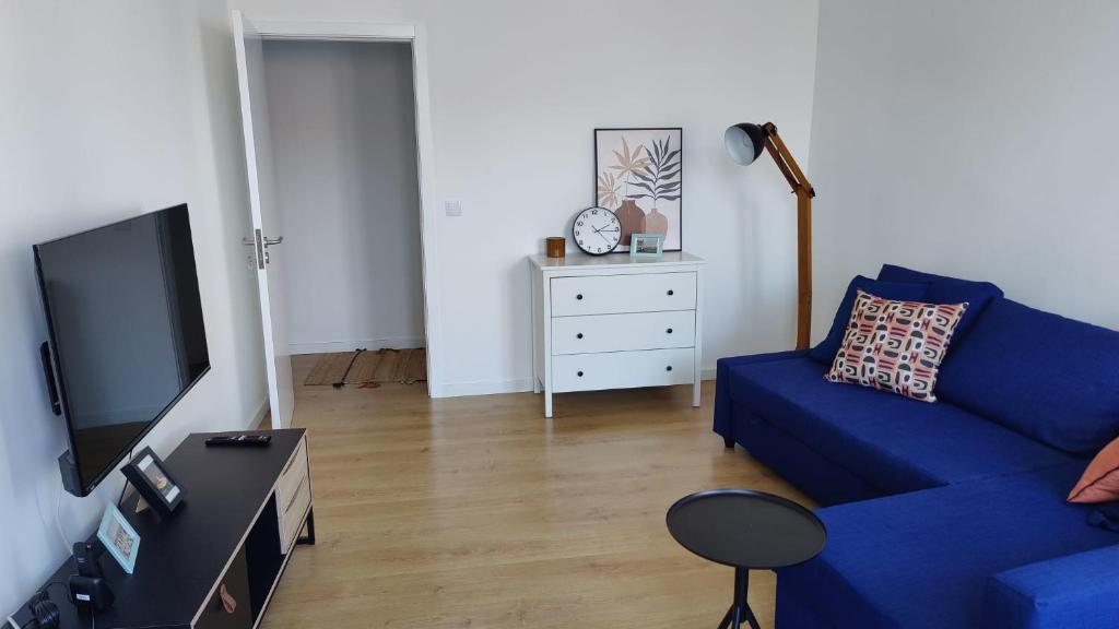 ein Wohnzimmer mit einer blauen Couch und einem Fernseher in der Unterkunft Casa ao centro - Apartamento Angrego in Angra do Heroísmo