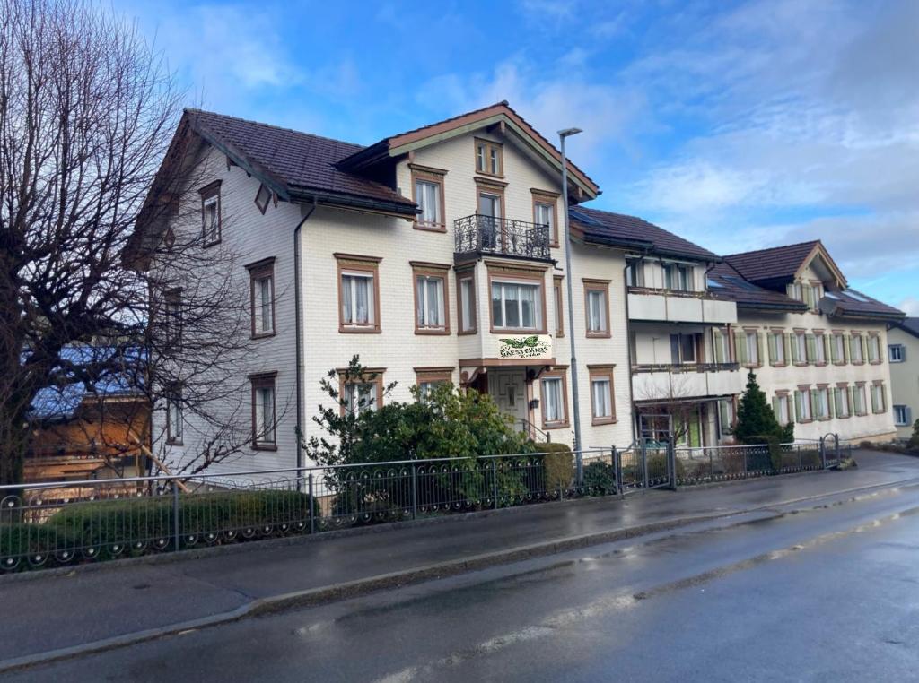 a white house with a fence on a street at 22 - Gästehaus Erika - Hundwil - Appenzellerland in Hundwil