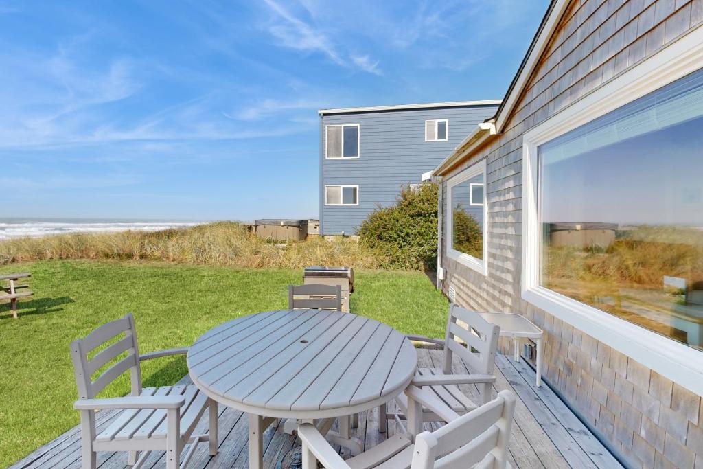 a table and chairs on a deck with a view of the ocean at Breakers Cottage in Rockaway Beach
