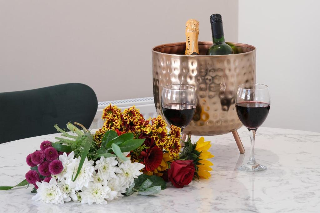 - une table avec deux verres de vin et un bouquet de fleurs dans l'établissement Harington's Apartments - John Street, à Bath