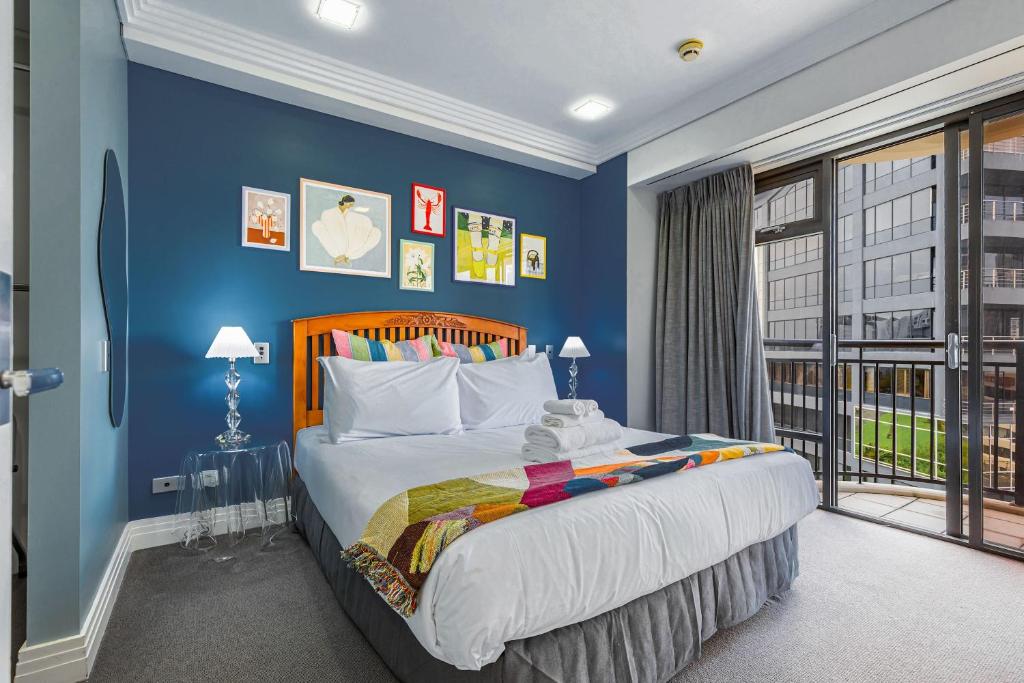 a bedroom with a bed with blue walls and a window at Boutique Apt in the Heart of Auckland Zodiak Stays in Auckland