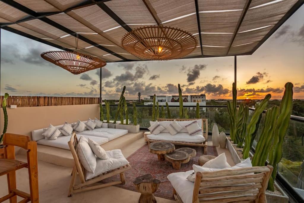 a living room with couches and tables and a sunset at Luxury 3 bdr at Aldea Zama, Private Pool! in Tulum