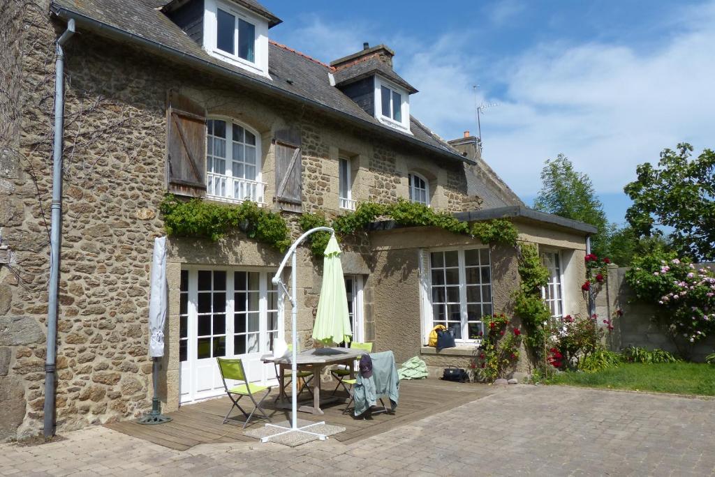 an old stone house with a table and an umbrella at Maison pour familles et amis in Dinard