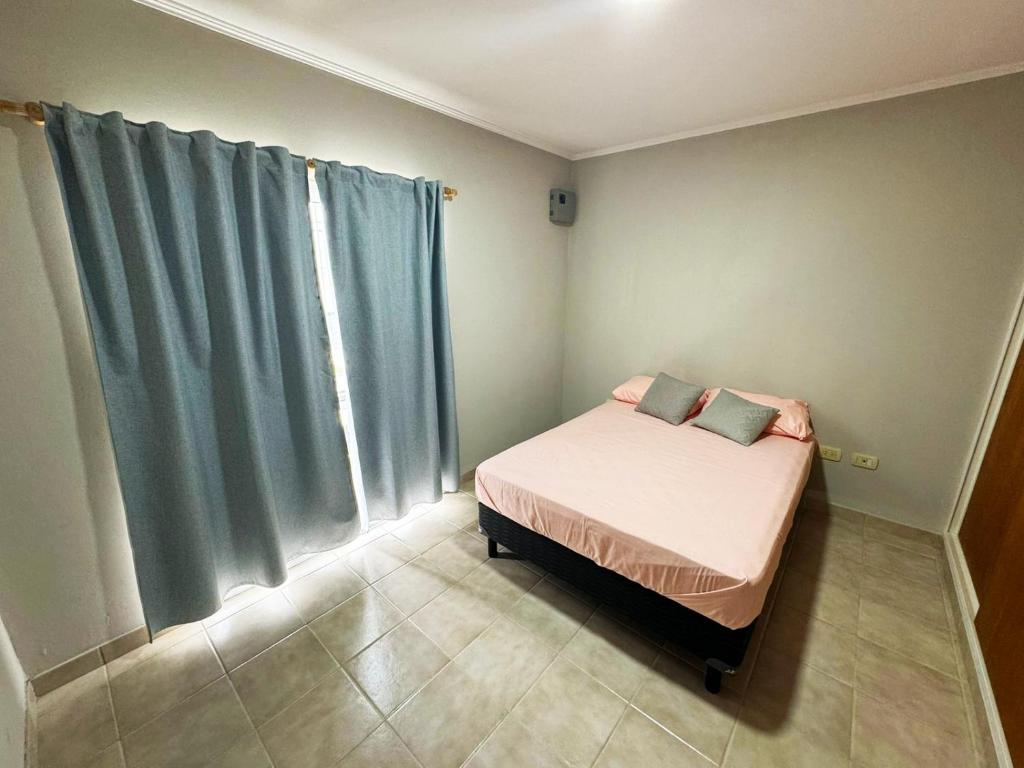 ein kleines Schlafzimmer mit einem Bett und blauen Vorhängen in der Unterkunft EL DEPTO DE GRACE in San Pedro