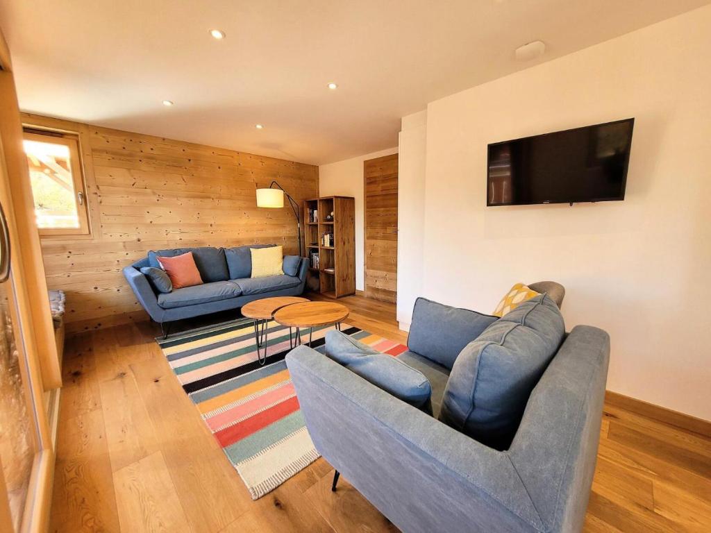 un salon avec deux canapés bleus et une télévision dans l'établissement Résidence Ambrocella - Très bel appartement, lumineux, bel espace de vie MAE-0781, aux Gets