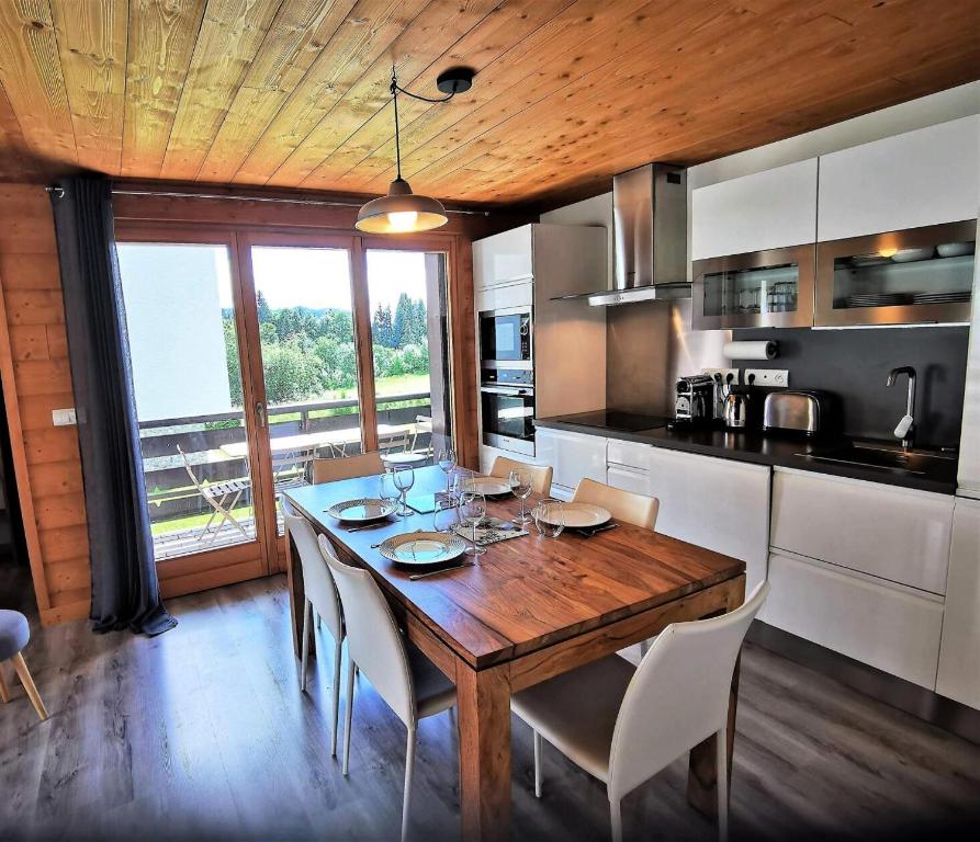 - une cuisine avec une table à manger en bois et des chaises dans l'établissement Résidence Le Plein Sud - très bel appartement classé 4, rénové avec soin et bien équipé MAE-1011, aux Gets