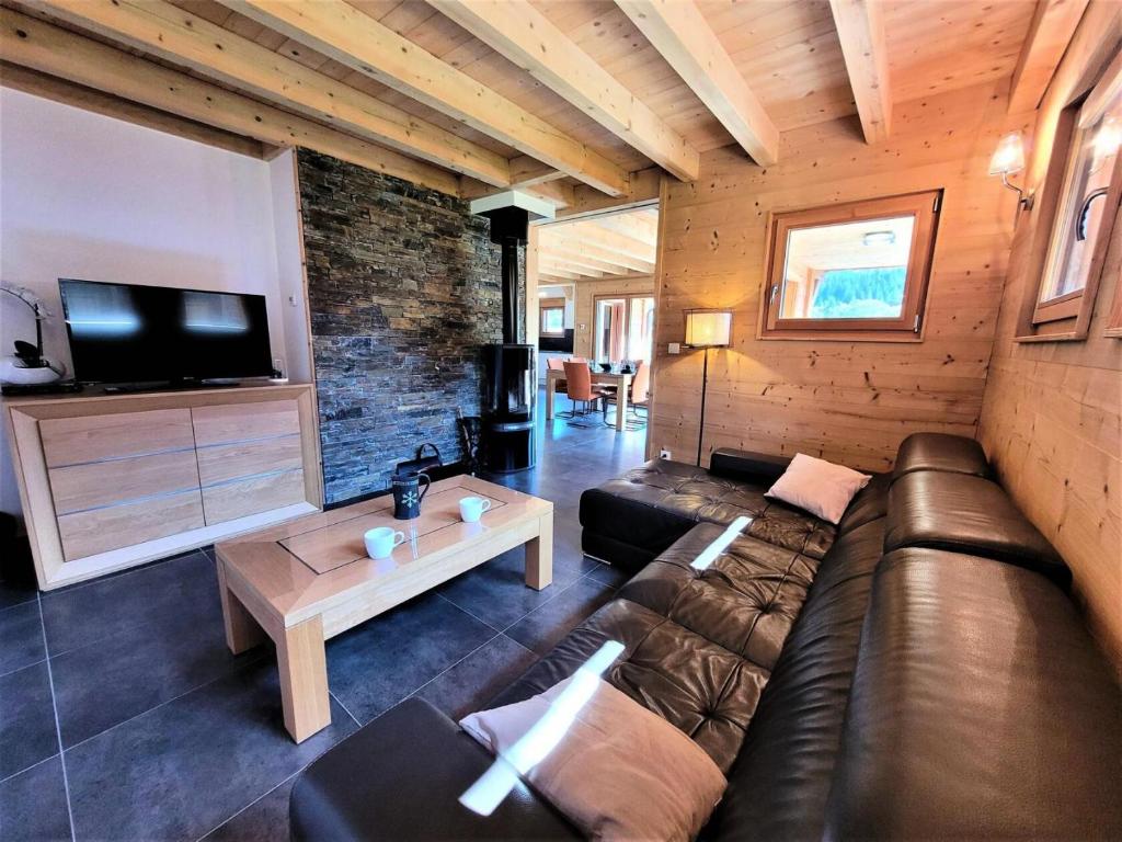 un salon avec un canapé en cuir et une télévision dans l'établissement Chalet Source Des Granges - Chalet Source des Granges - Calme et confort MAE-0991, aux Gets