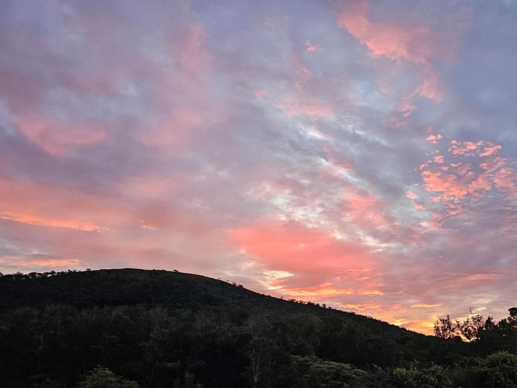 a sunset over a hill with a sky at CreaDora Hotel & Agrotourism Farm in La Estrella